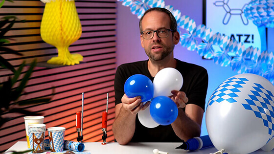 Stefan zeigt, wie man bei der Ballondeko fürs Oktoberfest, die aufgeblasenen Ballone zusammen verknüpft.